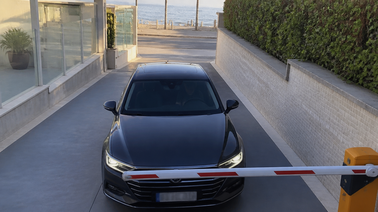 Carro na entrada da garagem de um prédio de praia com a cancela abrindo pela leitura da placa